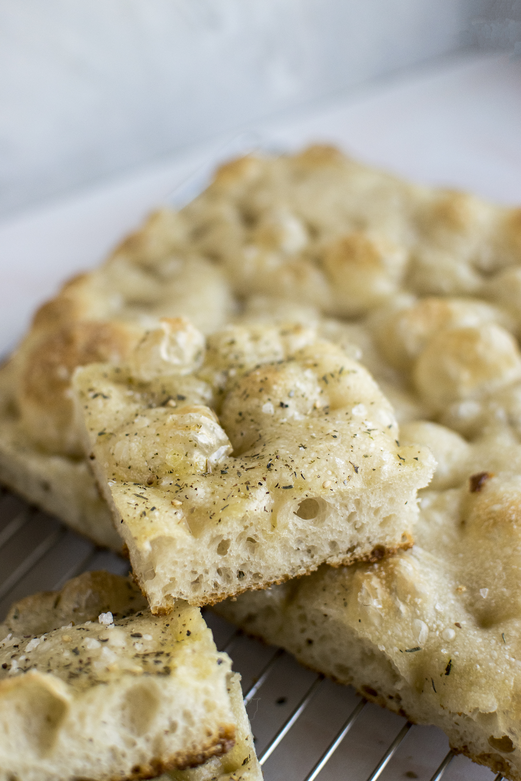 One piece of focaccia in focus. Sourdough focaccia, with za'atar on top and flakey salt