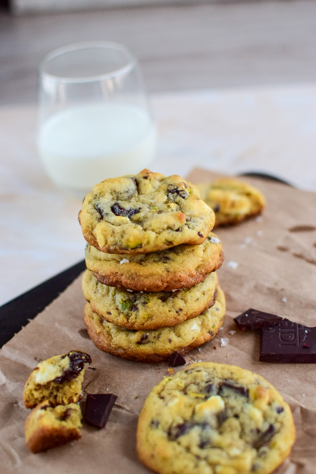 Chocolate cookies stacked on brown paper, with a glass of milk