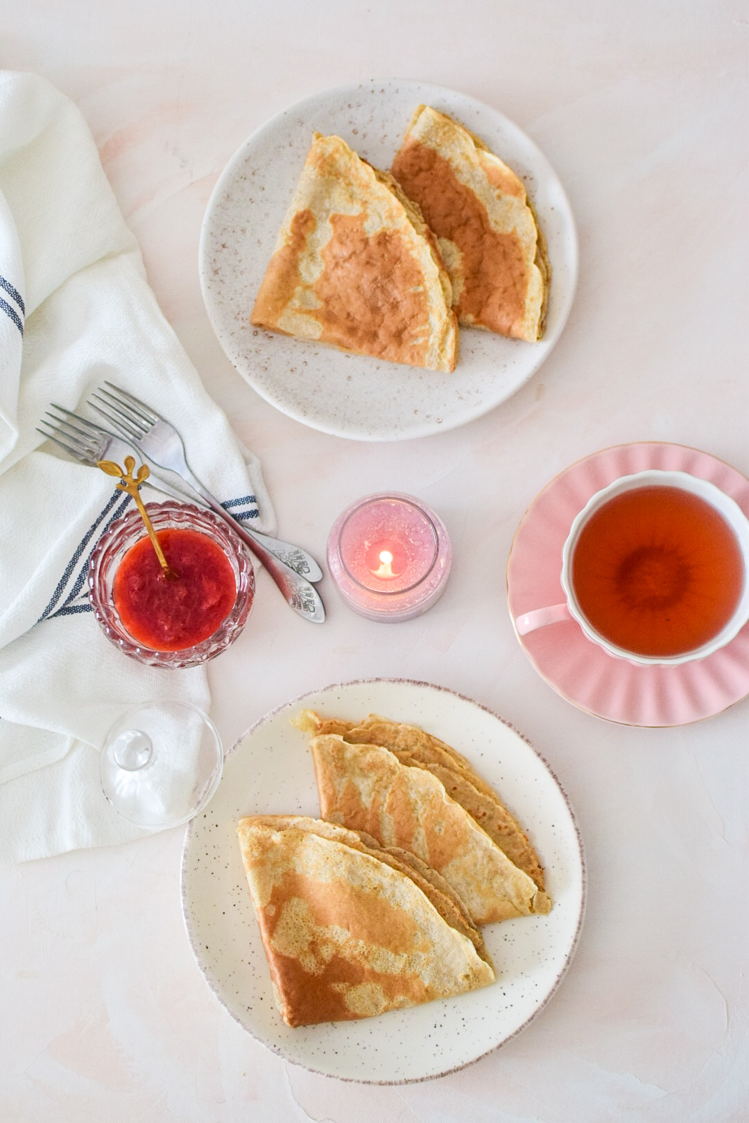 Oatmeal crepes in a cozy setting with candles and strawberry jam and fruity tea. 