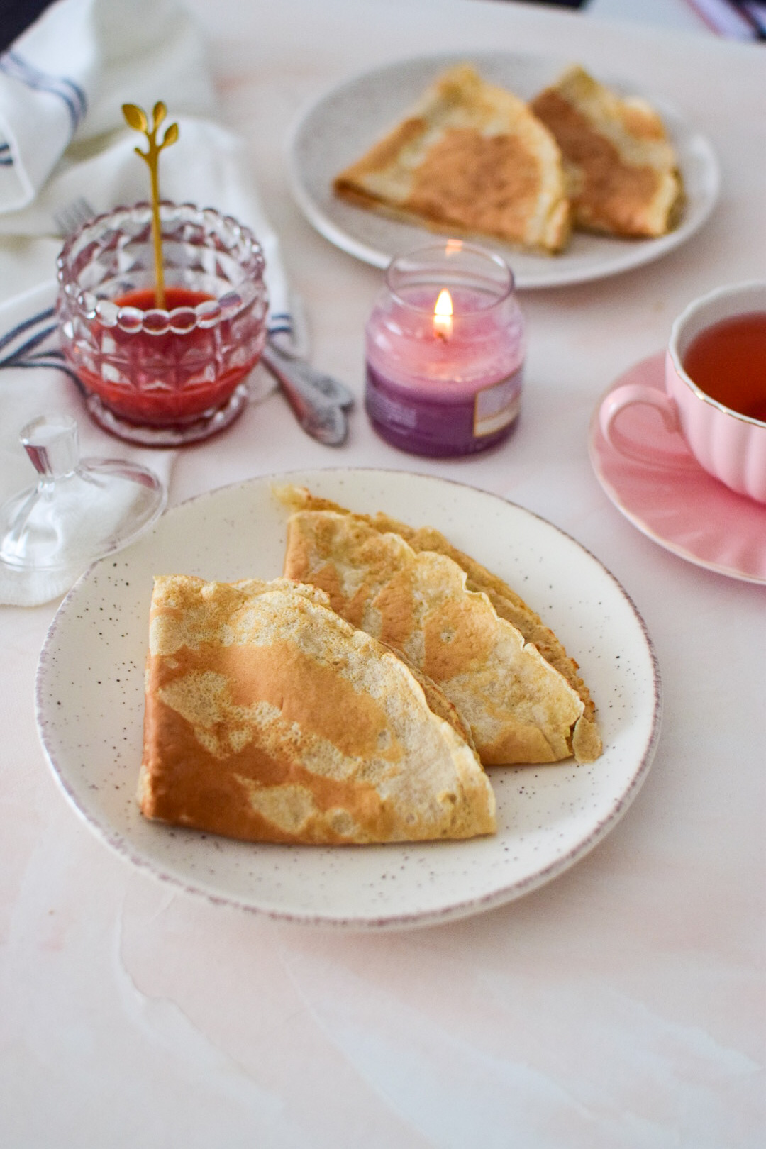 Oatmeal crepes in a cozy setting with candles and strawberry jam and fruity tea. 